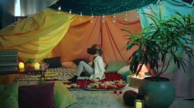 Orta kahverengi saçlı genç bir çocuk ev kulaklığıyla tuhaf bir şekilde oynuyor ve eğlenirken çok iyi vakit geçiriyor..