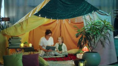 Bir çocuğun vaktini annesiyle geçirdiği çok sağlıklı bir an ve annesi ona rahatça oturdukları bir kitaptan bir hikaye okurken kahkahalarla güldüğü. 4k