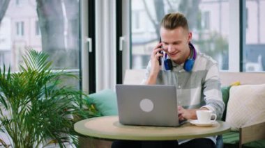 Modern kahve dükkanı, akıllı telefonuna cevap veren ve internetteki derslerini verip kahve içen iri yarı öğrenci. ARRI Alexa Mini 'de çekilen