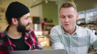 Kameranın önünde büyük, geniş bir kahve dükkanı. İki iyi arkadaş, laptopta bir şey izlerken eğlenmek için kafeteryada karizmatik bir şekilde buluşuyorlar. 4k