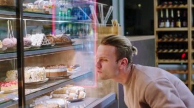 İyi görünümlü erkek müşteri çok mutlu ve karizmatik fırın kafedeki vitrinden taze tatlı seçiyor. 4k