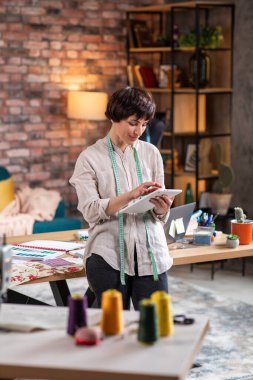 Modern terzi atölyesinde fotoğraf makinesinin önünde poz veren terzi kadın portresi..