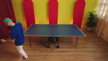 Ping pong maçını kazandıktan sonra kameranın önünde dans eden heyecanlı genç adam raketini tutuyor ve kendini harika hissediyor.