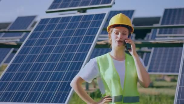 在摄像机前 漂亮的年轻生态工程师女性在光伏太阳能公园笑着 她用智能手机解释了一些事情 — 图库视频影像