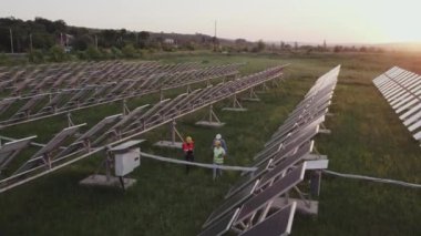 Güneş enerjisi istasyonunda İHA kuşlarının bakış açısıyla çekim yapan ekoloji mühendisleri, güneş panelleri yeşil enerji ve doğa ortamını tartışıyorlar. 4k