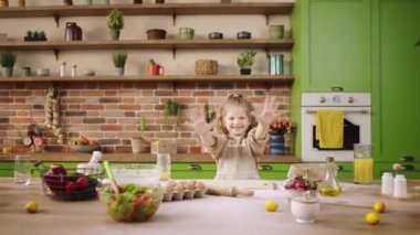 Kameranın önünde güzel bir kız mutlu ve gülümseyen büyük bir gülümsemeyle kameraya el sıkışırken tüm aile için lezzetli bisküvileri hazırlıyor. 4k