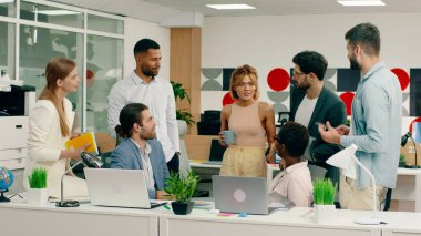 Modern bir iş merkezinde çalışan iyi görünümlü ofis çalışanları ve yöneticiler sabah bir toplantı yapar ve bazı görev listelerini tartışırlar..