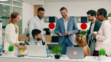 Takım elbiseli bir iş merkezi müdüründe, meslektaşları ve çok ırklı ofis çalışanlarıyla birlikte diğer işçiler sandalyelerde otururken bir tartışma içerisindeler. Portre