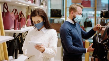 Küçük işletme kavramı ve Coronavirus denetçisi salgınında girişimci ürünlerin fiyatlarını değiştirmek için dijital tablet kullanırken diğer müşteriler dükkana girip