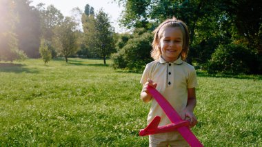 Kameranın önünde karizmatik gülümseyen tatlı bir çocuk kırmızı bir uçakla çok tatlı poz veriyor..