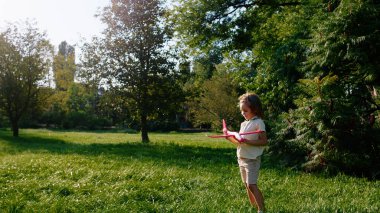 Güneşli bir günde uçakla parkın ortasında çimlerin arasından koşan küçük bir çocuk..