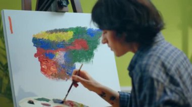 Artistik bir kadının, güzel bir sanat eserini tuvale resmederken ve rahat bir pozisyonda otururken yakın plan bir fotoğrafı. ARRI Alexa Mini 'de çekilen