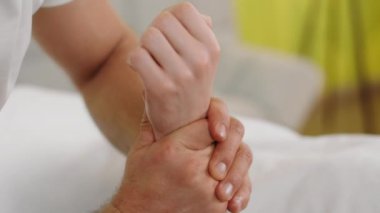 Spa salonunda, müşteri masaj masasında yatarken, masör kameraya yakın çekimde müşterisinin elleriyle masaj yapıyor. 4k