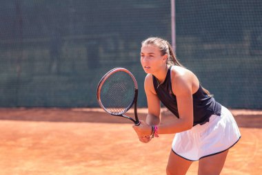 Tenis maçında tenis kortunda profesyonel oyuncu kadın topa vuruyor ve atletik vücudu olduğu için heyecanlanıyor..