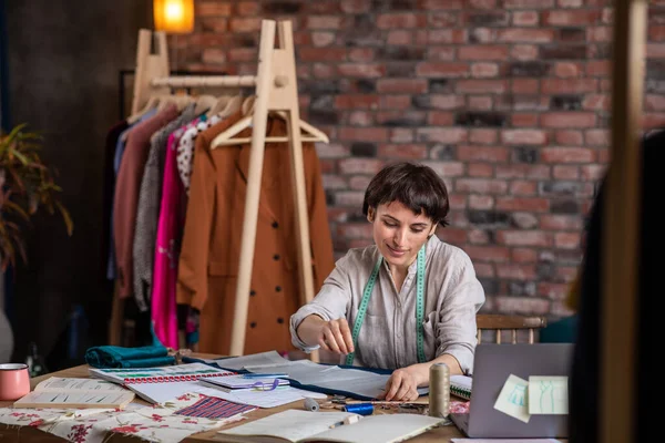 tailor woman working on clothes in tailoring atelier. beautiful young female fashion designer working tailoring new handmade dress in workshop.