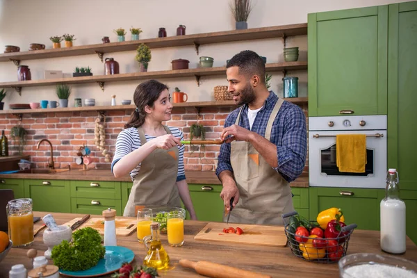 Mutlu çok ırklı çift birlikte yemek pişiriyorlar. Mutfak adasında sebze kesiyorlar ve birlikte çok mutlular..