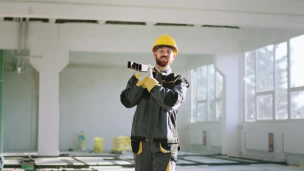 在镜头前 建筑工人拿着安全设备 带着建筑材料在镜头前走过建筑工地 — 图库视频影像