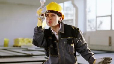 Özel üniformalı, güvenlik eldivenli, çalışkan kadın müteahhit inşaat malzemelerini boyamak için fırçayı kullanıyor. ARRI Alexa Mini 'de çekilen.