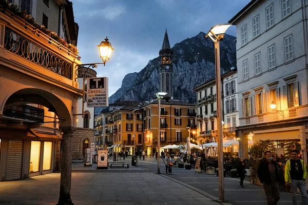 Downtown city street scene at the evening. Lecco, Italy. Picturesque town overlooking lake Como. Square XX Settembre near the old Viscontea tower. Historic center of Lecco city 