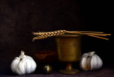 still life with metal bowl and garlic on a dark background