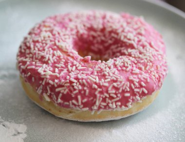 Beyaz arka planda pembe kremalı donut.