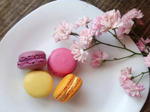 macaroons with pink flowers on white plate