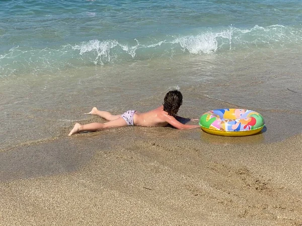 Dziewczynka Leżąca Plaży Nadmuchiwanym Pierścieniem Tle Morza — Zdjęcie stockowe