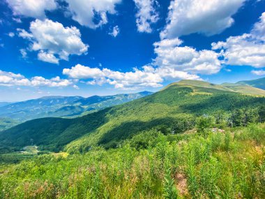 Dağları ve mavi gökyüzü olan güzel bir manzara.