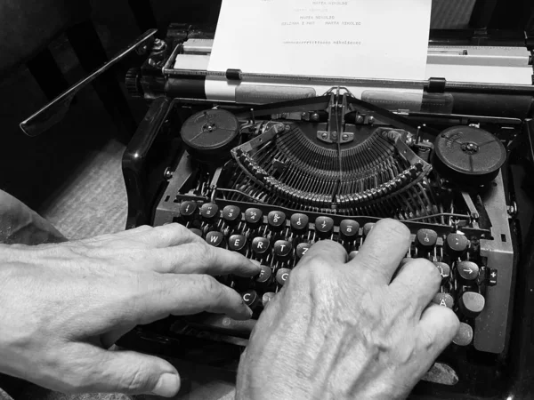 man typing on an old typewriter in black and white