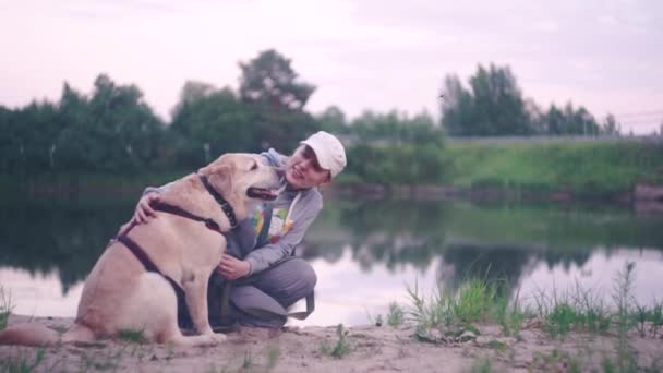 Seorang Gadis Dengan Anjing Labrador Retriever Duduk Pasir Dekat Air — Stok Video