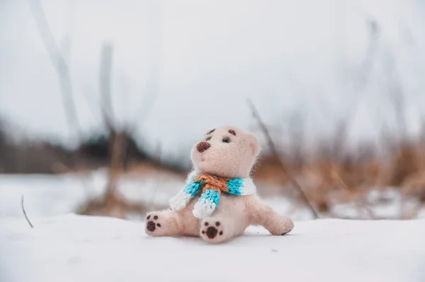 スカーフの中のおもちゃのホッキョクグマは雪原に座って春を待っています — ストック写真