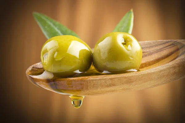 Aceitunas con aceite de gota sobre cuchara de madera —  Fotos de Stock