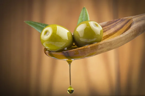 Olivy s drop olejem na dřevo lžíce — Stock fotografie