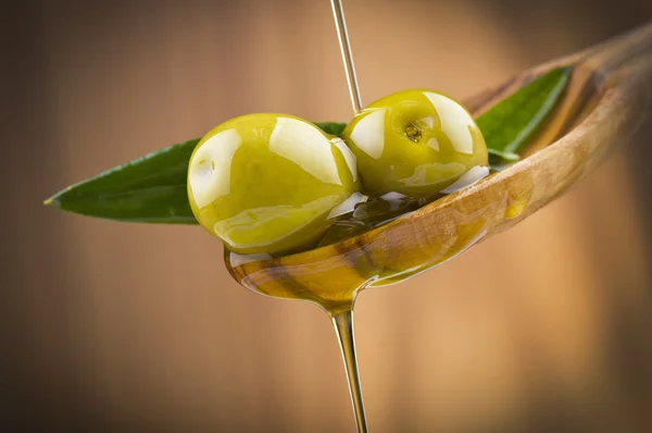 Olivy s drop olejem na dřevo lžíce — Stock fotografie