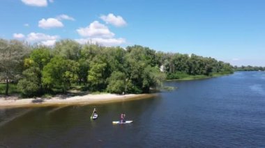 Nehir manzaralı insanlar nehirde dinleniyor, kano ve su kayağı yapıyorlar.