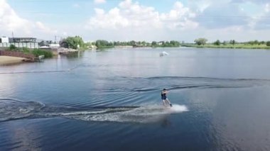 Genç adam yazın gün batımında nehirde wakeboard kullanıyor.
