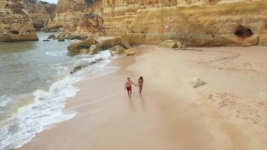 Portekiz sahilinde mayo giymiş genç ve güzel bir çiftin hava manzarası.