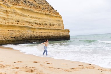 Genç ve güzel bir kız Portekiz sahilinde Atlantik Okyanusu 'nun arka planında eğleniyor.