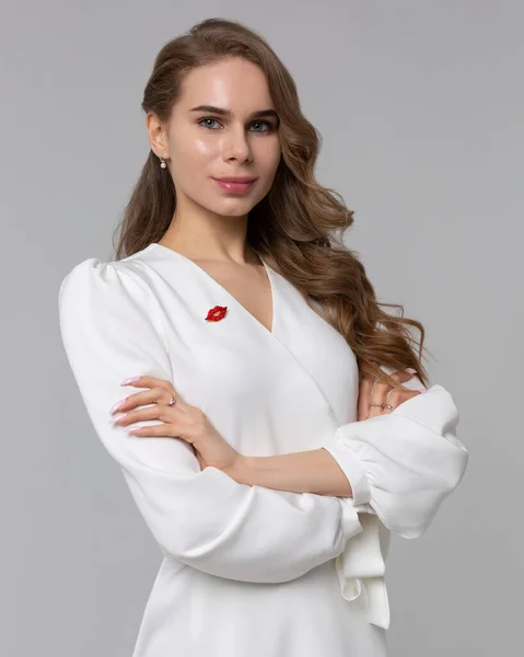 Welcome to our beauty salon. Portrait of mature cosmetologist in white lab coat looking at camera with smile while posing arms crossed at her clinic