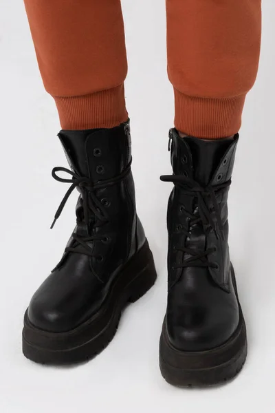 A man (male, boy) wearing military shoes (combat military boots) and cargo pants at the studio.