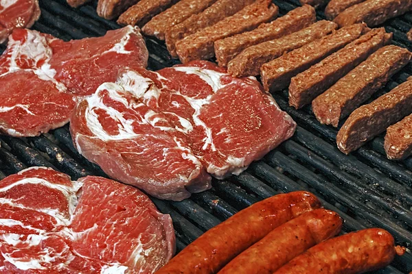 Salsicce rumene e carne rossa su una griglia . — Foto Stock