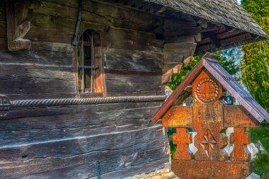 Romanya 'nın Maramures ilçesi Targu Lapus' a ait Rogoz köyüne özgü geleneksel haçlarla süslemeli ahşap haç. Arka planda eski ahşap kilise duvarı.