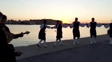RETHYMNO, CRETE, GREECE - 17 Haziran 2021: Geleneksel kostümlü Yunan dansçılar Port Rethymno-Rethymno Marina 'da günbatımında halk dansı yaptılar.