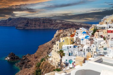 Yunanistan 'ın Santorini adasındaki Oia köyünün kubbeleri, kiliseleri, otelleri ve restoranları olan tipik beyaz ve mavi mimari.