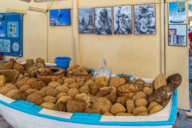 SYMI, GREECE - 3 Temmuz 2022: Dermatolojik tıbbi özelliklere sahip geniş bir doğal deniz süngeri koleksiyonu eski bir profil mağazasına getirildi. Duvardaki dalgıçların eski resimleri.