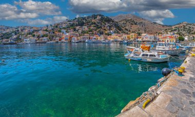 SYMI, GREECE - JULY 3, 2022: Symi harbour, with colorful neoclassical mansions covering the slopes near the main city. Part of the Dodecanese island chain. Sister city with Tarpon Springs, Florida