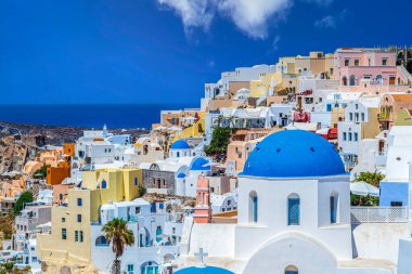 OIA, SANTORINI ADLAND, GREECE - 21 Haziran 2021: Yunanistan 'ın Santorini adasındaki Oia köyünün kubbeleri, kiliseleri, otelleri ve restoranları olan tipik beyaz ve mavi mimari.
