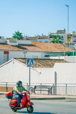 Bir adam İspanya sokaklarında motosiklet sürüyor.