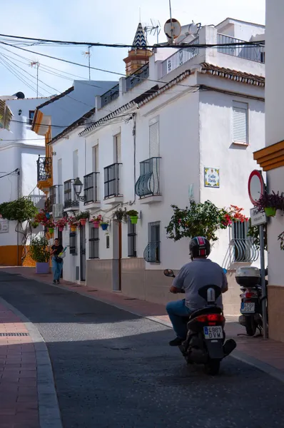 Bir adam İspanya sokaklarında motosiklet sürüyor.