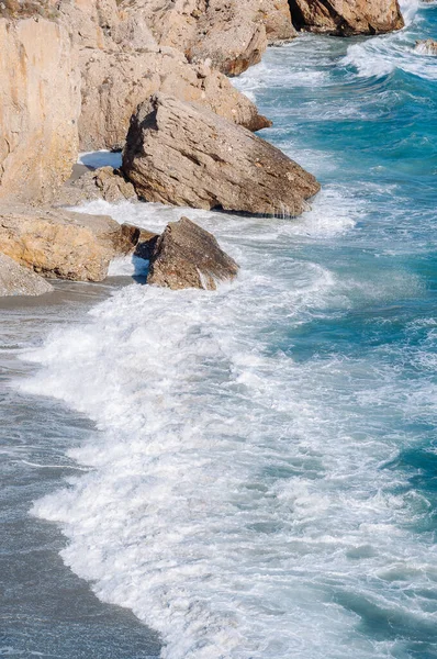 Vista aerea dall'alto delle onde del mare che colpiscono rocce sulla spiaggia con acqua di mare turchese. — Foto Stock